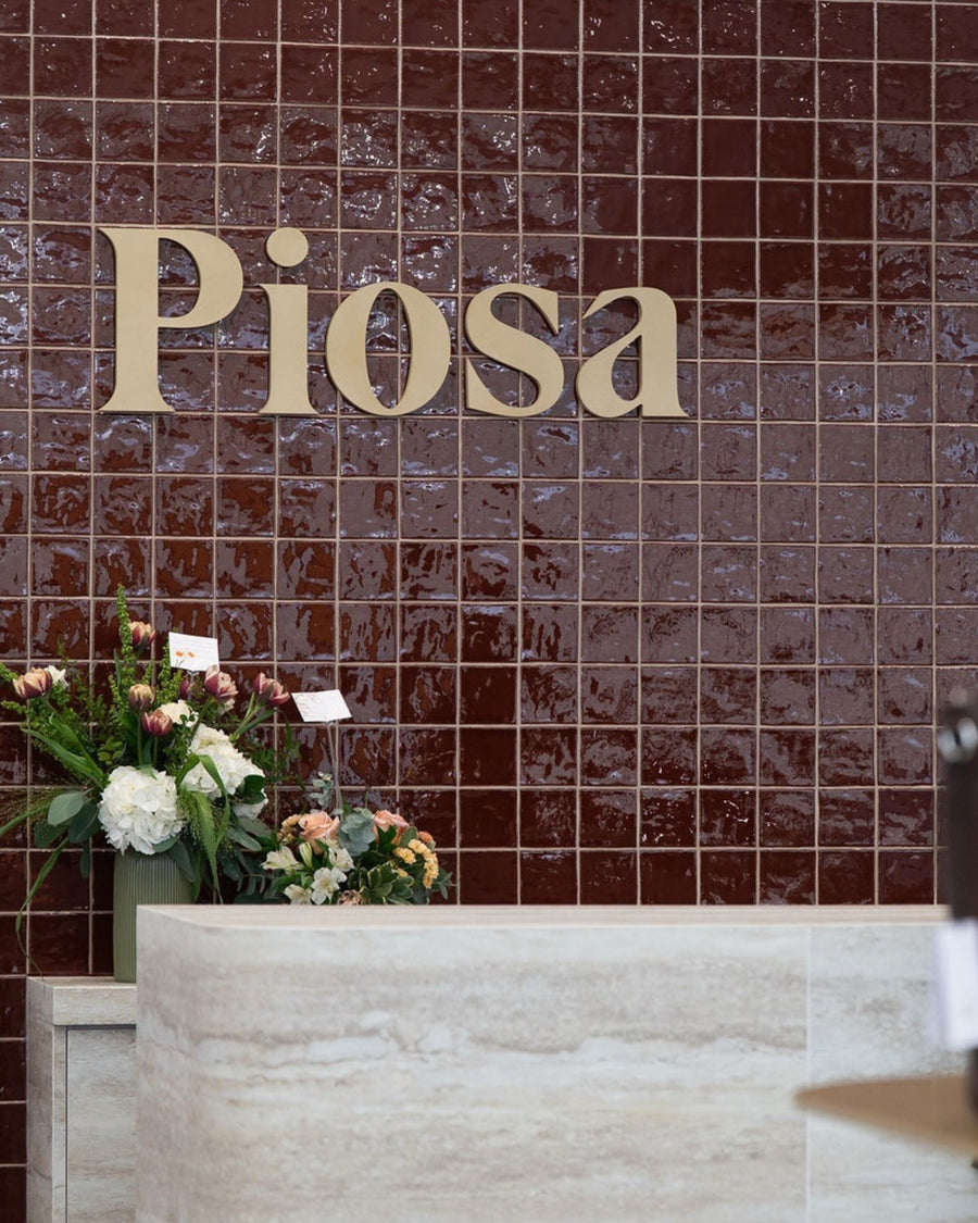 Comptoir de caisse de la boutique Piosa habillé du panneau flexible travertin beige BétonFlex, devant le mur au logo Piosa