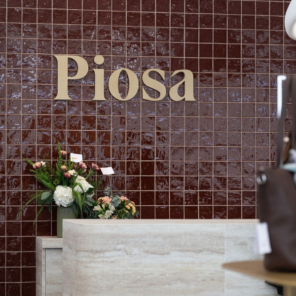 Comptoir de caisse de la boutique Piosa habillé du panneau flexible travertin beige BétonFlex, devant le mur au logo Piosa