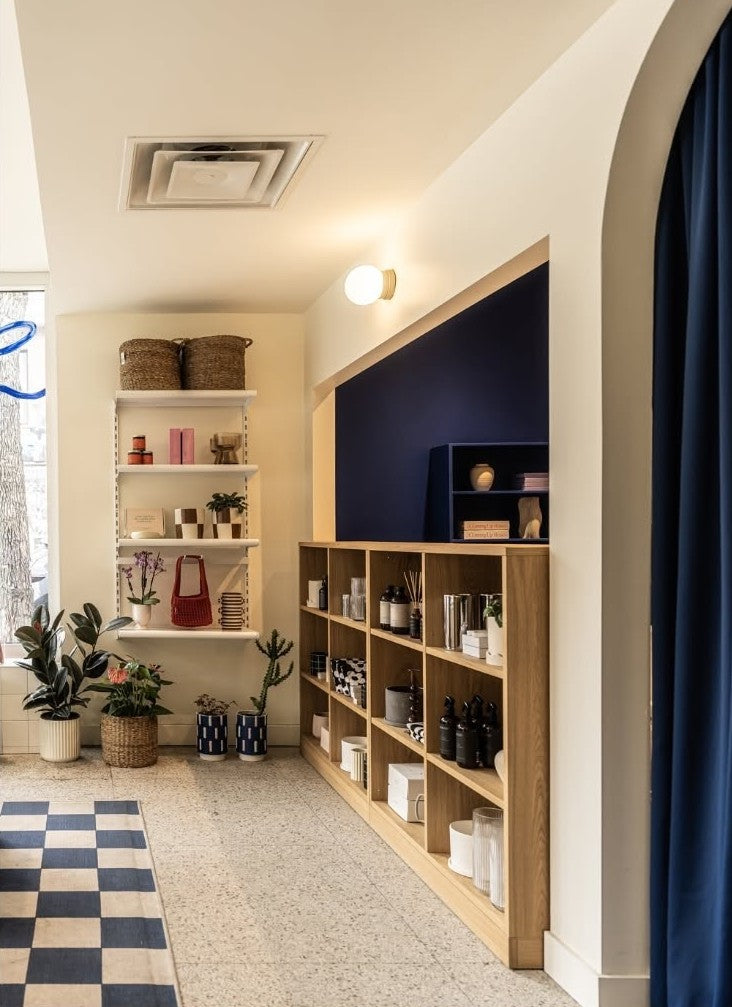Coin boutique de Flori Flora : étagères en bois, rideau bleu et sol en damier