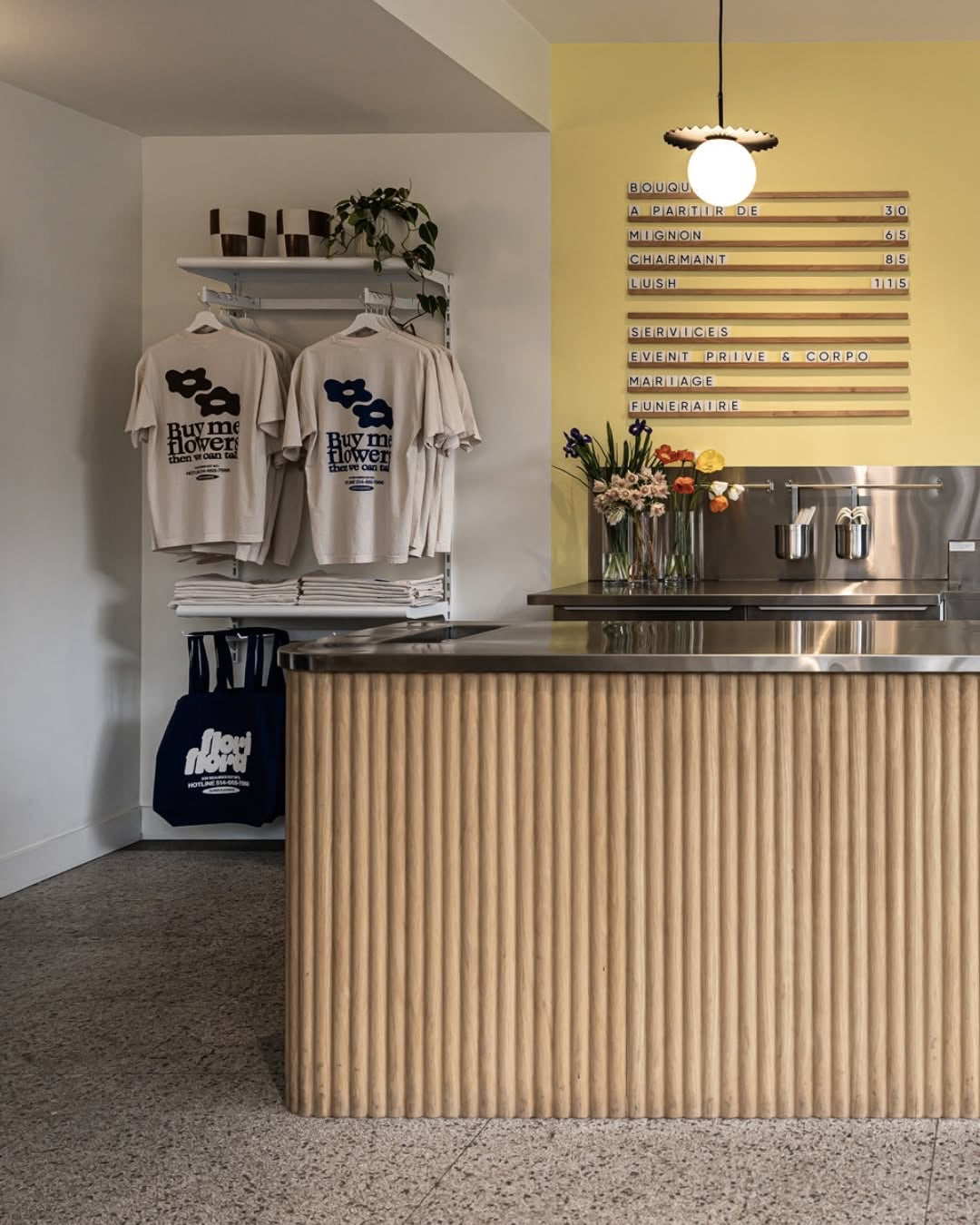 Comptoir en panneau flexible tambour chêne naturel devant le mur jaune de la boutique Flori Flora