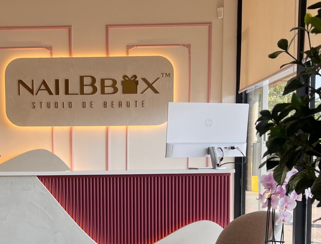 Comptoir du studio de beauté NailBbox : panneau flexible tambour peint en rouge sous le logo lumineux