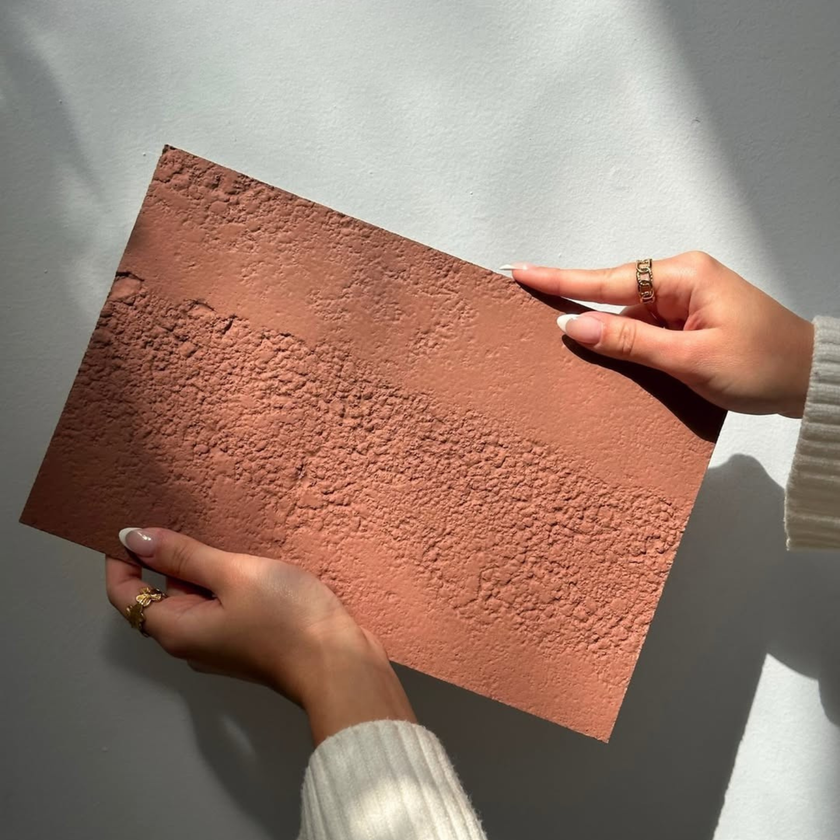 Main tenant un panneau mural qui fait effet des murs de pierre au maroc, terre cuite